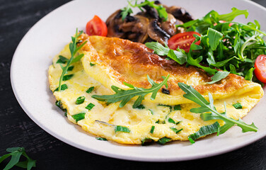 Omelette with cheese, green herbs and fried mushrooms on plate.  Frittata - italian omelet