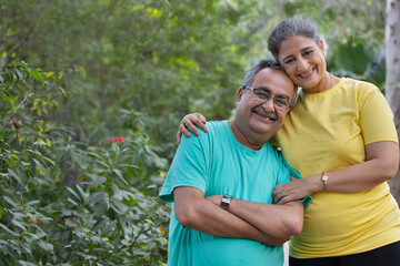 A HAPPY HUSBAND AND WIFE LEANING ON EACH OTHER AND POSING