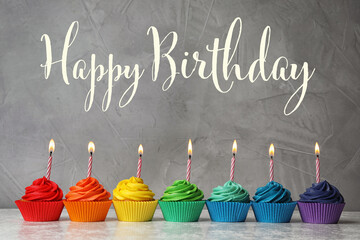Happy Birthday! Delicious cupcakes with burning candles on table