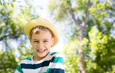 Kid boy in a straw hat smiles in the summer in nature. Summer holidays
