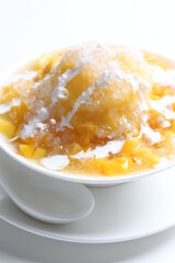 chilled fresh mango fruit sago ice snow kacang sweet dessert with coconut milk cream in white bowl