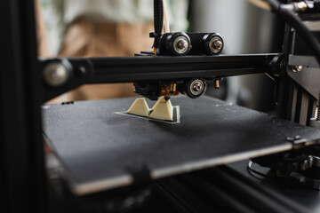 Fototapeta na wymiar close up view of 3D printer creating plastic figure in modern office