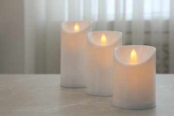 Fototapeta na wymiar Glowing decorative LED candles on grey table. Space for text
