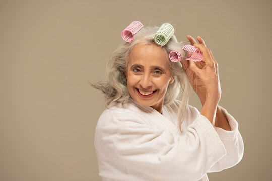 An Old Woman Styling Hair With Rollers.