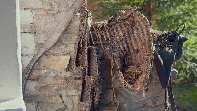 Rustic rural concept, antique handmade traditional russian bast shoes. Video. Pairs of bast shoes hanging on the old brick house wall, old fashioned products of birch bark.