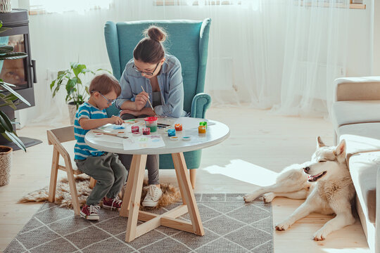 Mom and child paint together at home with dog
