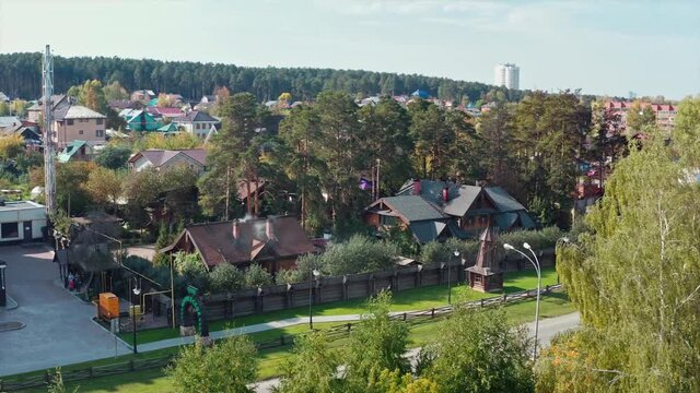 Beautiful small village with brick cottages located in ecological place. Video. Aerial view of modern village houses surrounded by forest on a summer day.