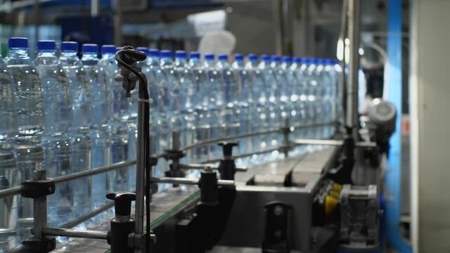 Bottles with a volume of 1.5 liters of water moves along the conveyor. Production of mineral water in the shop of the food industry plant
