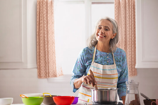 An Old Woman Cooking In Her Kitchen.