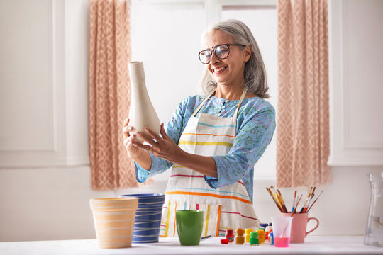 An old woman looking at the vase she is about to paint.