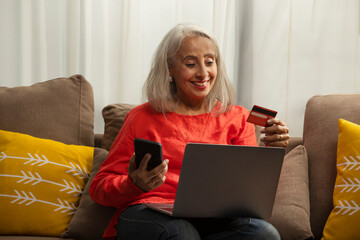 An old woman placing an order on her laptop with credit card.