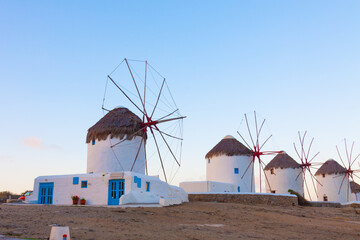 Windmills in a row from distance at dawn with partialy blue sky Mykonos island cyclades Greece