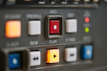 Close up of the control panel of an old broadcast tape recorder where we can see the playback buttons and the focus on the red rec button.