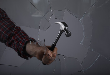 Man breaking window with hammer on grey background, closeup - obrazy, fototapety, plakaty
