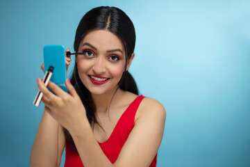 Close-up portrait of young woman applying mascara