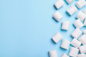Delicious puffy marshmallows on light blue background, flat lay. Space for text