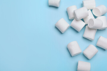 Fototapeta na wymiar Delicious puffy marshmallows on light blue background, flat lay. Space for text