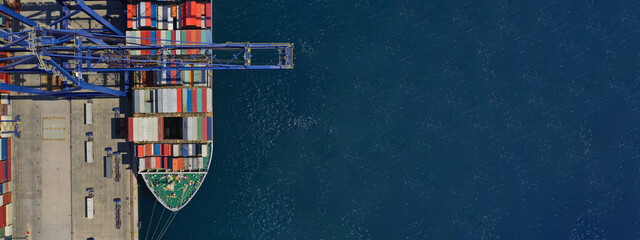 Aerial top down ultra wide photo of industrial container ship loading  - unloading colourful truck...
