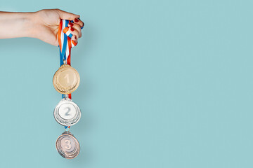 Woman's hand holding three medals (gold,silver,bronze).concept of award and victory.copy space