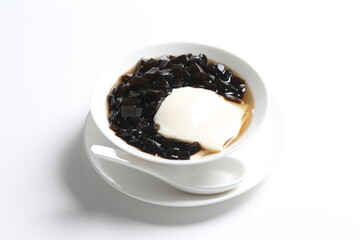 black herbal jelly with white soya milk pudding and sweet syrup in white bowl yuan yang traditional dessert menu