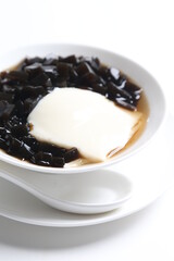 black herbal jelly with white soya milk pudding and sweet syrup in white bowl yuan yang traditional dessert menu