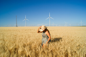 Young woman with hat walking around green energy park with windmills in Andalucia,Spain