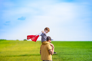 Dad with his little son walking in the field holding flag of Poland. Fathers day in Poland. Polish...