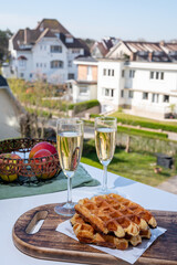 Breakfast with fresh baked belgian waffles and brut champagne sparkling wine in flute glasses served on outdoor bistro terrace in France