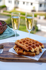 Breakfast with fresh baked belgian waffles and brut champagne sparkling wine in flute glasses served on outdoor bistro terrace in France