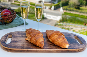 Breakfast with fresh baked croissants and  brut champagne sparkling wine in flute glasses served on outdoor bistro terrace in France