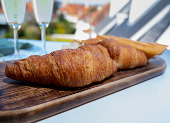 Breakfast with fresh baked croissants and  brut champagne sparkling wine in flute glasses served on outdoor bistro terrace in France