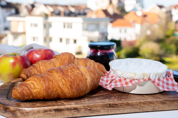 Fototapeta na wymiar French breakfast with fresh baked croissants and cheeses from Normandy, camembert and neufchatel served outdoor with nice city view