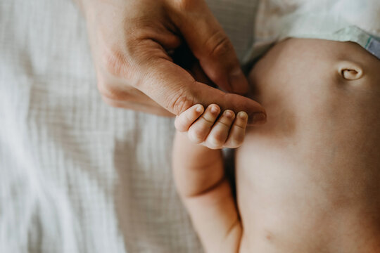 Closeup of small baby hand holding her father's finger.