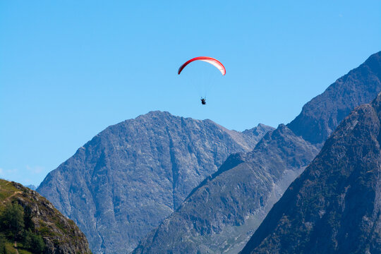 Paraplaners in tandem gliding in blue sky and Alpine mountains on paraplane