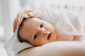 Closeup of a newborn baby held by his mother in her arms.