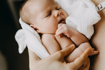 Closeup of a newborn baby sleeping in mother's arms. - obrazy, fototapety, plakaty