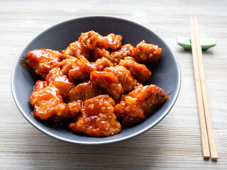 chinese cuisine - sweet and sour pork (guo bao rou) in gray bowl on wooden table