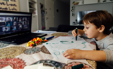 Little preschool boy in a online classes at his home. Small child drawing. The small kid is drawing.