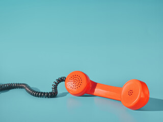 Orange telephone receiver on blue background