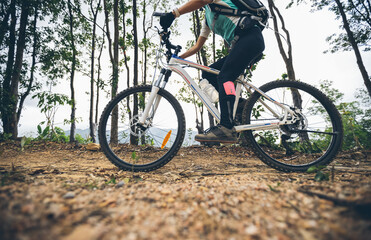 Fototapeta na wymiar Woman cycling on mountain top forest trail