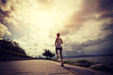 Fitness woman running on sunny coast trail
