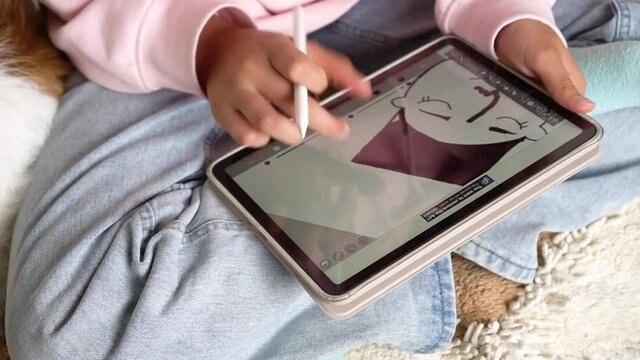 Focused stylish teenage girl painting using Apple Pencil on IPad tablet and watching online course on phone while practicing at home. Online training, online classes. Russia, Tatarstan, June 15, 2021.
