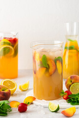 Jugs of fresh refreshing fruit drinks with fruit wedges, summer cold juices with ice