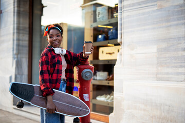 Portrait of happy african-american woman with skateboard. Young stylish woman with skateboard outdoors