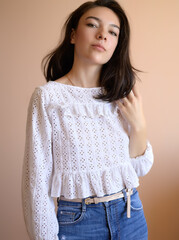 Beautiful young woman posing on beige wall background.