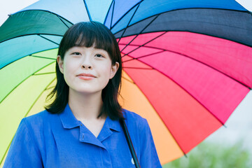 雨の中、カラフルな傘を指す女性