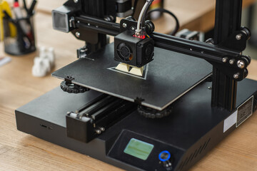 Fototapeta na wymiar 3D printer creating plastic model on table in modern office