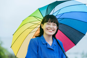 雨の中、カラフルな傘を指す女性