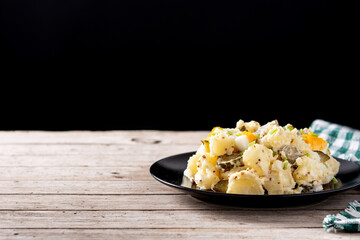 Potato salad with gherkins, egg and mustard on wooden table. Copy space