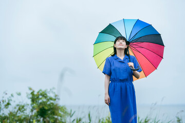 雨の中、カラフルな傘を指す女性